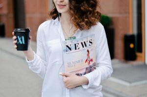 A woman holding a coffee cup and a newspaper called News